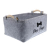 A gray felt pet toy storage basket with wooden handles.