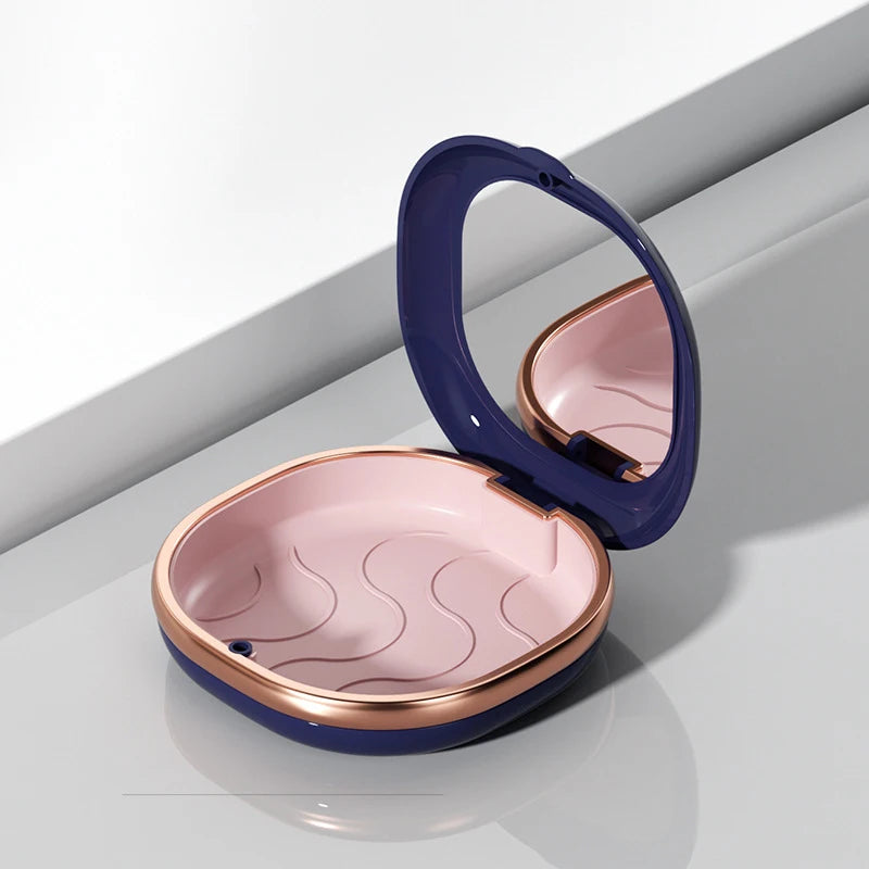A compact orthodontic retainer case in navy blue with a rose gold finish, shown open on a light gray surface.