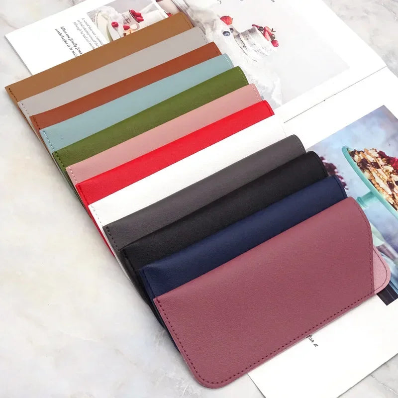 Colección de fundas protectoras para gafas de cuero PU en tonos marrón, verde, rosa y azul sobre una superficie blanca