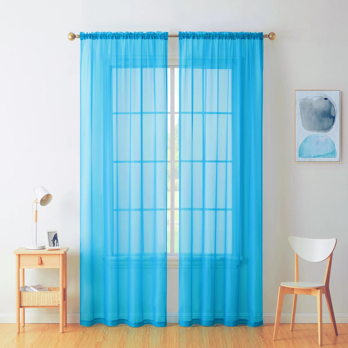 Two panels of sheer blue voile curtains hanging in a window frame.