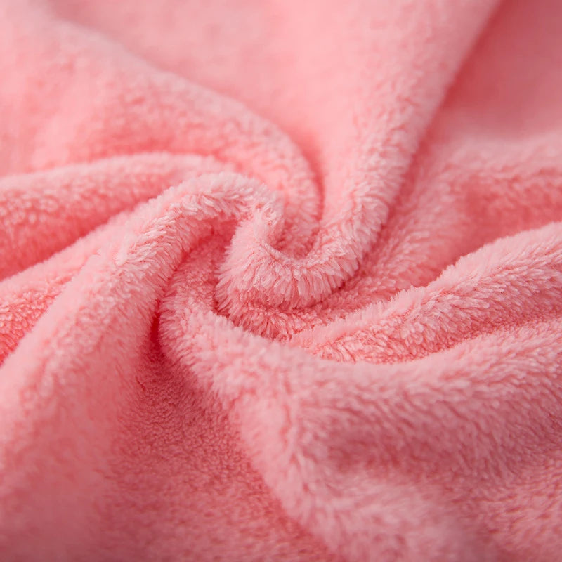 Close-up of soft coral pink velvet face towels folded into a swirl.