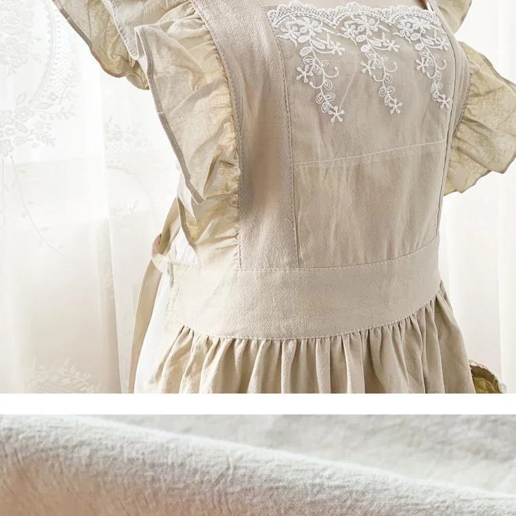 A light beige ruffled cotton linen kitchen apron featuring delicate white lace trim.