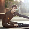 A young man wearing a black long-sleeved shirt is sitting outdoors, looking towards the camera.
