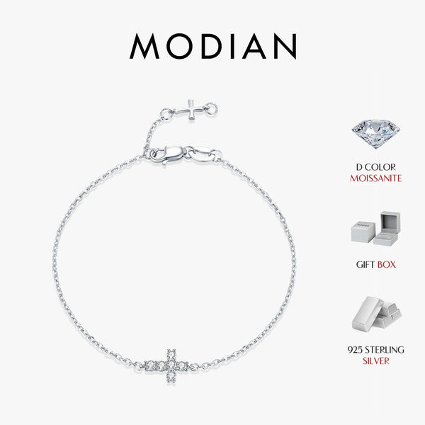 A silver minimalist bracelet featuring a double cross design set with a diamond-cut moissanite stone.