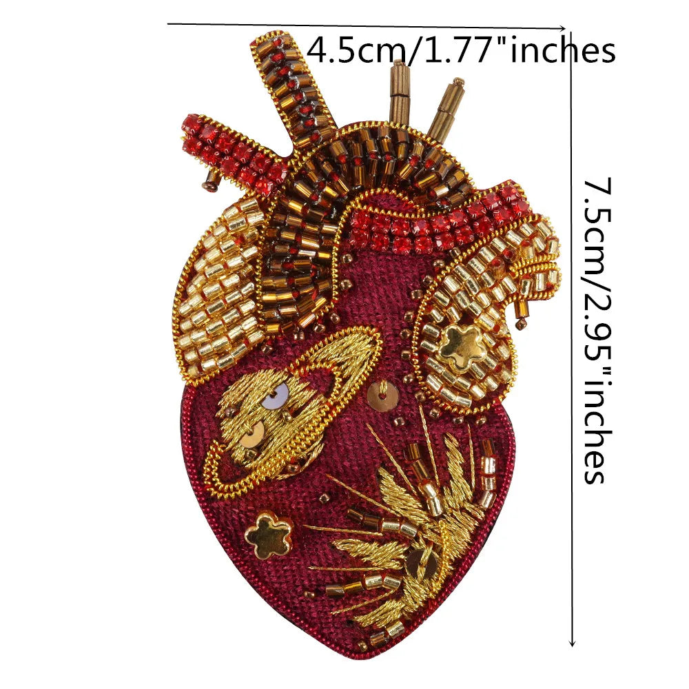 A detailed image of a large, heart-shaped patch made of red fabric and gold and red beads and rhinestones.