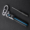A silver key fob with a black protective TPU cover and a metal tool is displayed on a dark surface.
