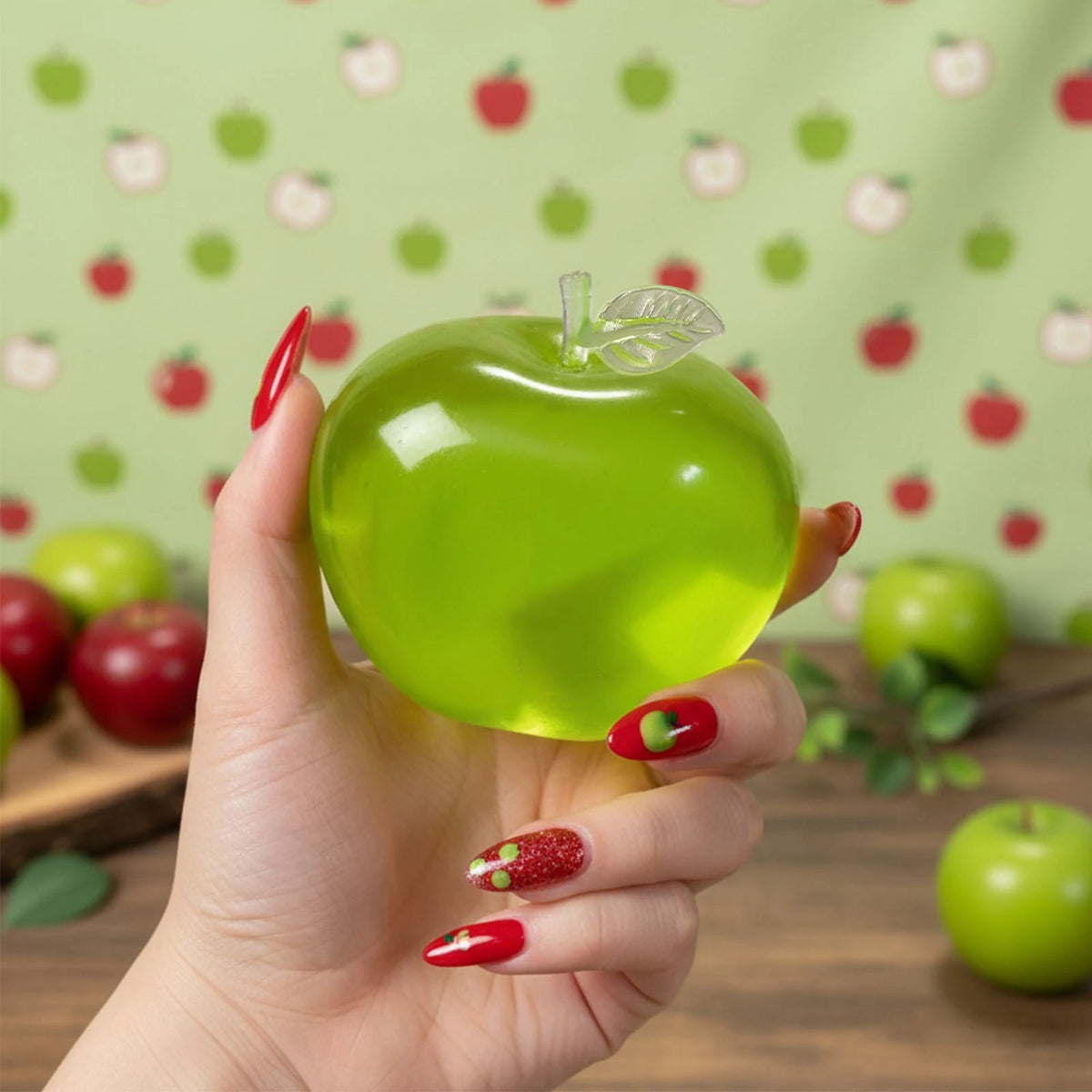 Eine Hand hält ein leuchtend grünes Apfel-Fidget-Spielzeug vor einem hellgrünen Hintergrund.
