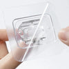 A hand holds a clear adhesive curtain rod hook clamp designed for nail-free use in showers and storage.
