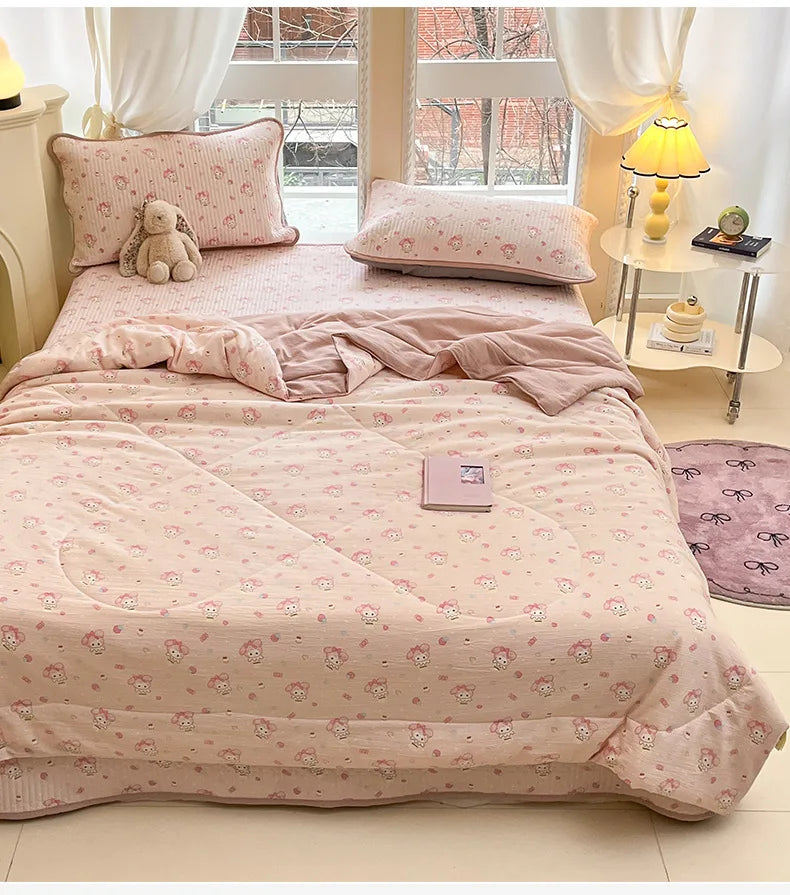 A pink cartoon pattern kids lightweight summer quilt displayed on a bed with white curtains and a stuffed animal.