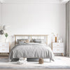 A bedroom featuring a bed with gray bedding and light wood furniture against a white wall.
