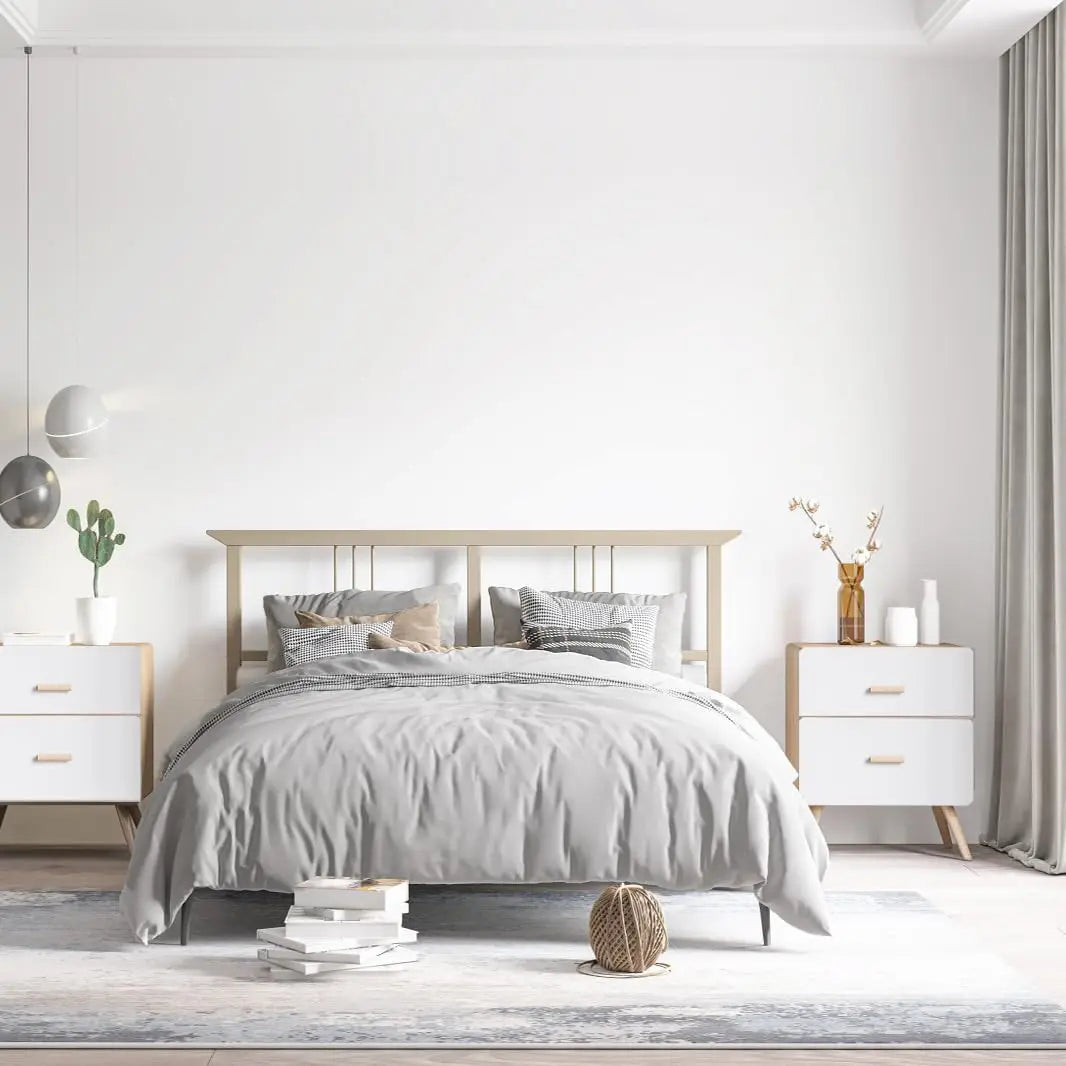 A bedroom featuring a bed with gray bedding and light wood furniture against a white wall.