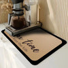 A silver glass coffee maker is placed on a brown diatomite coffee mat with the text Just Enjoy Our Life.