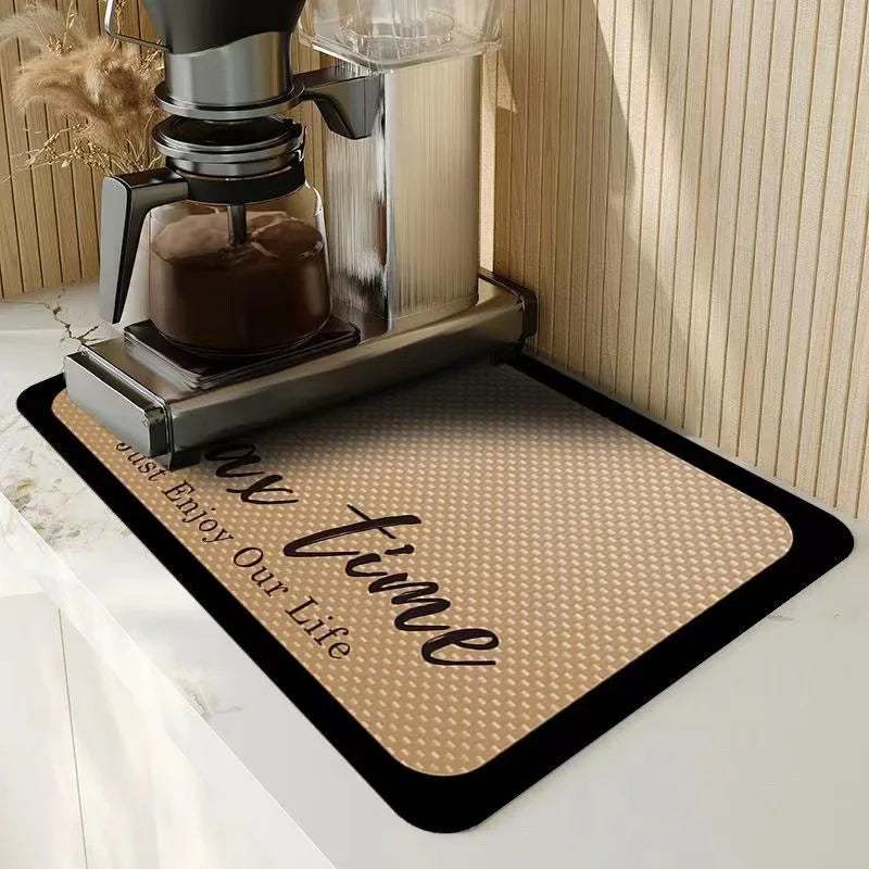 A silver glass coffee maker is placed on a brown diatomite coffee mat with the text Just Enjoy Our Life.