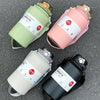 Three stainless steel tumblers in green, pink, and black are displayed on a gray surface.