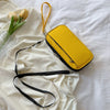 A yellow waterproof passport and document organizer wallet with a black strap is displayed on a white fabric background.