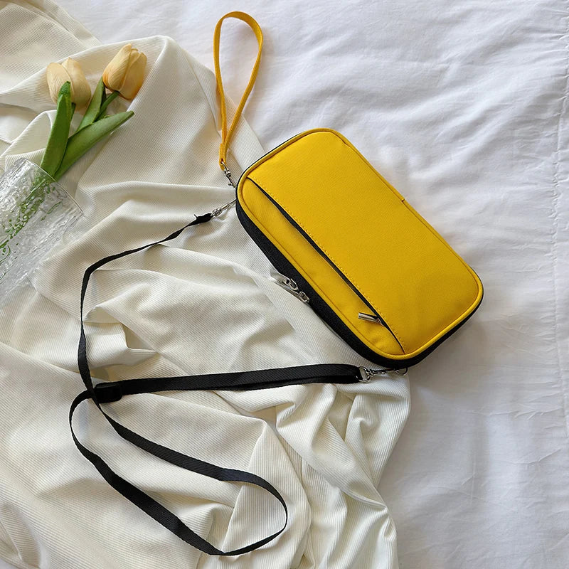 A yellow waterproof passport and document organizer wallet with a black strap is displayed on a white fabric background.