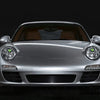 Silver Porsche headlight with a green LED devil eye feature and grille detail.