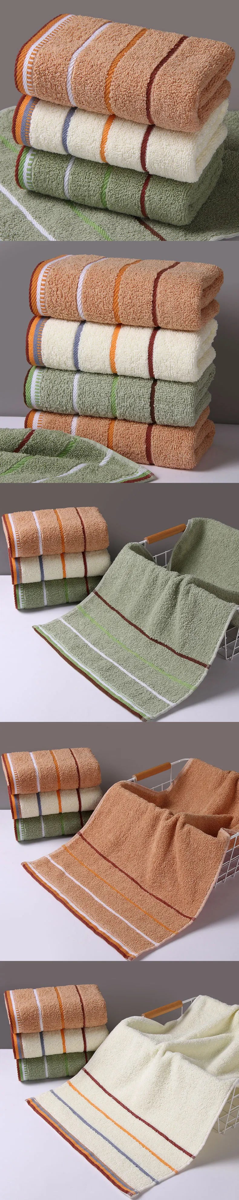 A set of stacked bath towels in earthy tones including beige, olive green, and terracotta.