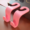 A pair of pink universal car seat headrest hooks are shown resting on a dark surface.