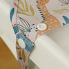 A close-up of a long-sleeve waterproof baby bib with a cute giraffe design, featuring light pink and teal patterns.