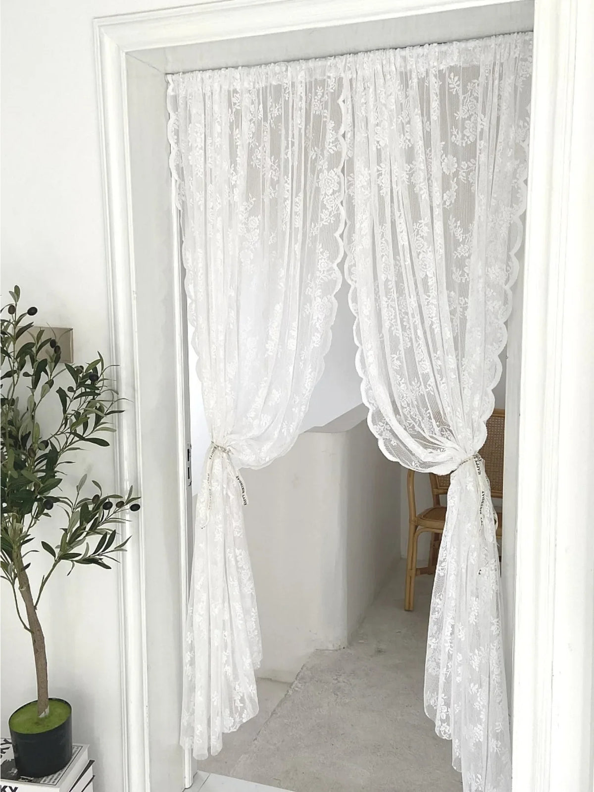 Rideau transparent à broderie florale blanche accroché dans une porte