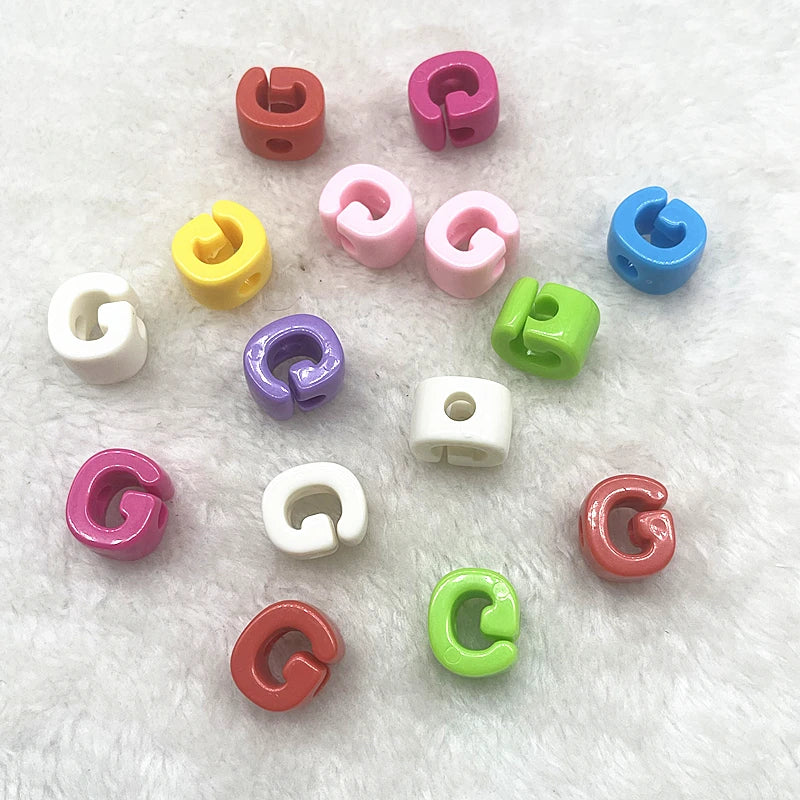 A collection of ten mixed alphabet letter beads in various colors including pink, purple, green, yellow, and blue.