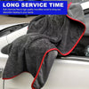 A dark gray microfiber car drying towel with a red trim is shown draped over a white car.