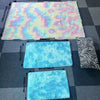 Three plush silk-touch area rugs in pastel colors and black zebra pattern displayed on a gray tiled floor.