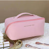 A pink leather travel makeup organizer bag with a zipper and pink piping resting on a white surface.