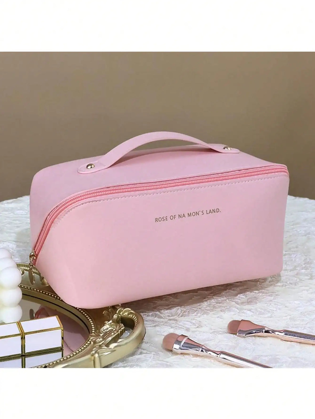 A pink leather travel makeup organizer bag with a zipper and pink piping resting on a white surface.
