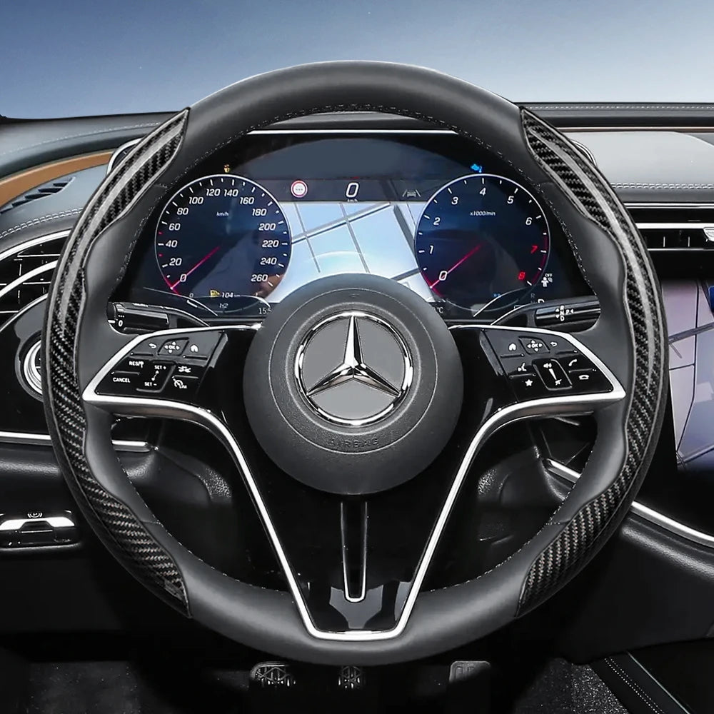 Close-up view of a black steering wheel with carbon fiber texture covers and Mercedes-Benz instrumentation