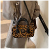 A brown leather retro leopard print hobo satchel bag is shown hanging from a gray blazer.