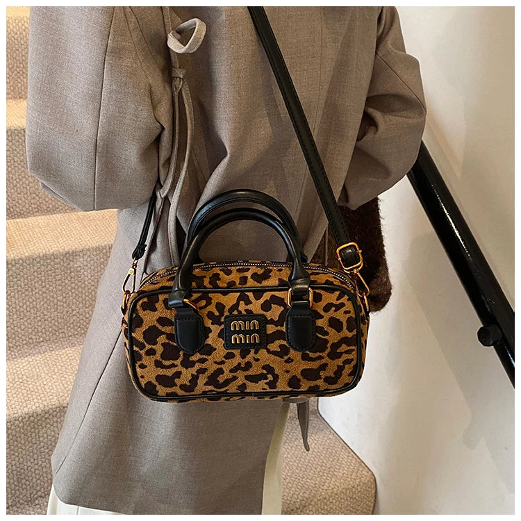 A brown leather retro leopard print hobo satchel bag is shown hanging from a gray blazer.