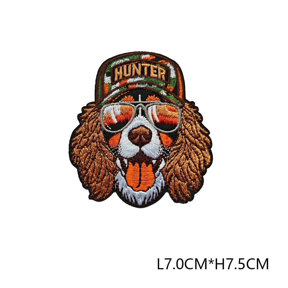 A brown embroidered hunting patch featuring a dog face wearing sunglasses and a hunter banner.