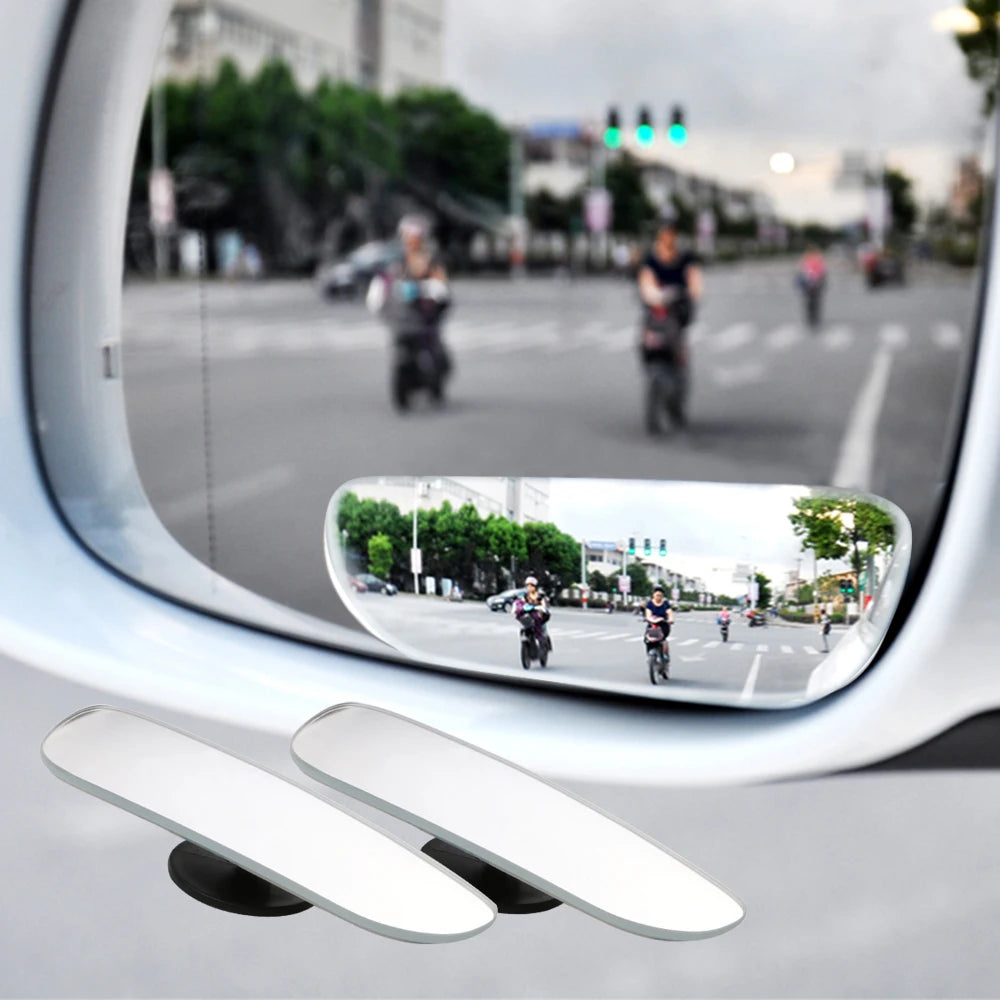 A wide-angle blind spot mirror mounted on a vehicle, showing the road and surrounding traffic.