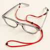 A pair of clear-framed glasses with a red adjustable lanyard and arms are displayed on a white background.