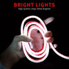 A hand is holding a flexible LED strip light that glows bright red and white in a coiled shape against a dark background.