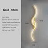 A vertical gold LED wall lamp with a curved design mounted on a light gray wall.