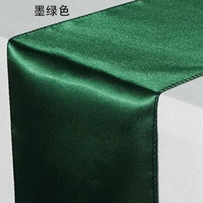 A close-up of an emerald green satin table runner fabric.