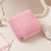A pink ribbed storage pouch for sanitary napkins and cosmetics resting on a white surface.