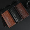 Portefeuille à fermeture éclair en cuir marron pour homme, ouvert sur une surface sombre.