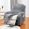 Housse de canapé jacquard grise décorative drapée sur une chaise avec des coussins blancs sur un sol en bois.