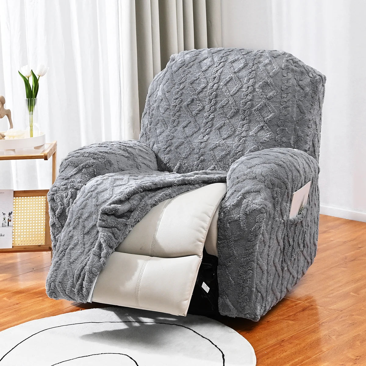 Housse de canapé jacquard grise décorative drapée sur une chaise avec des coussins blancs sur un sol en bois.