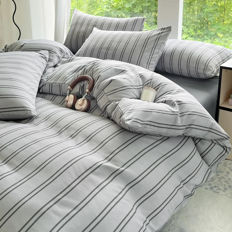 A gray and white striped duvet cover set with two pillowcases and a matching pillow on a bed.