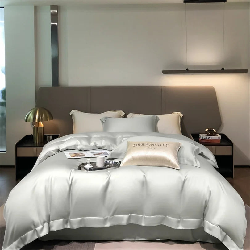 Luxuriöses Bett mit silberner Bettwäsche und Kissen vor neutraler Wand in einem modernen Schlafzimmer.