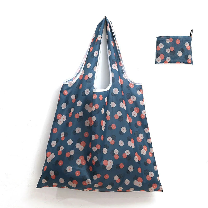 A navy blue reusable shopping tote bag with a floral pattern and an attached fabric carry pouch.