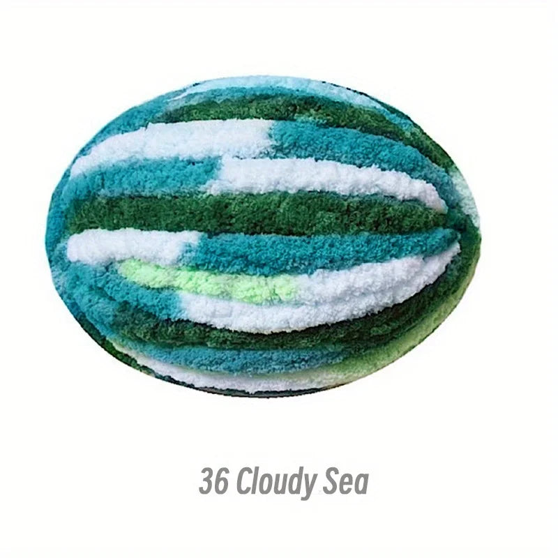 A spherical craft ball made of green and blue chenille yarn with white stripes, titled Cloudy Sea.