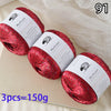 Three spools of red glitter yarn for knitting and crafting displayed on a light surface.