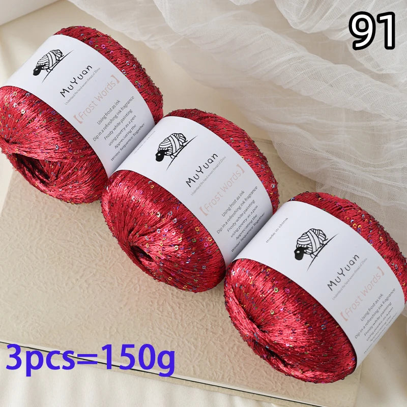 Three spools of red glitter yarn for knitting and crafting displayed on a light surface.