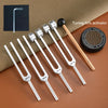 A set of tuning forks with activators showing various frequencies including 128, 136, 256, and 384 Hz placed on a brown surfa